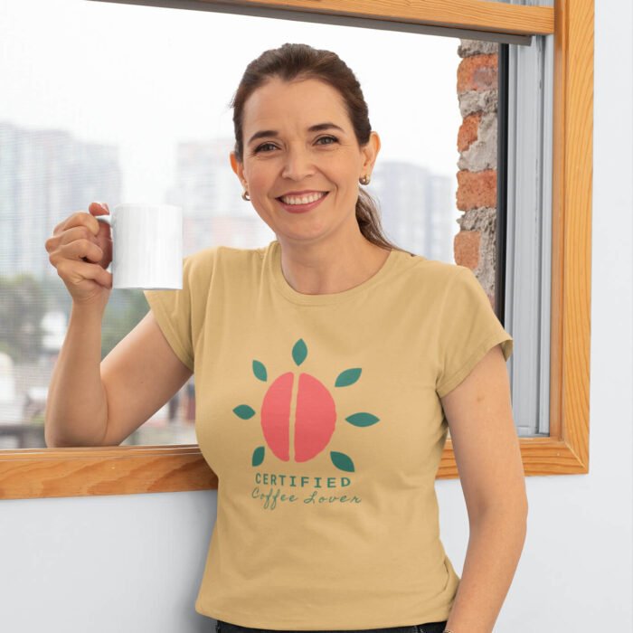 t-shirt-mockup-of-a-middle-aged-woman-holding-an-11-oz-coffee-mug-by-a-window-31602.png